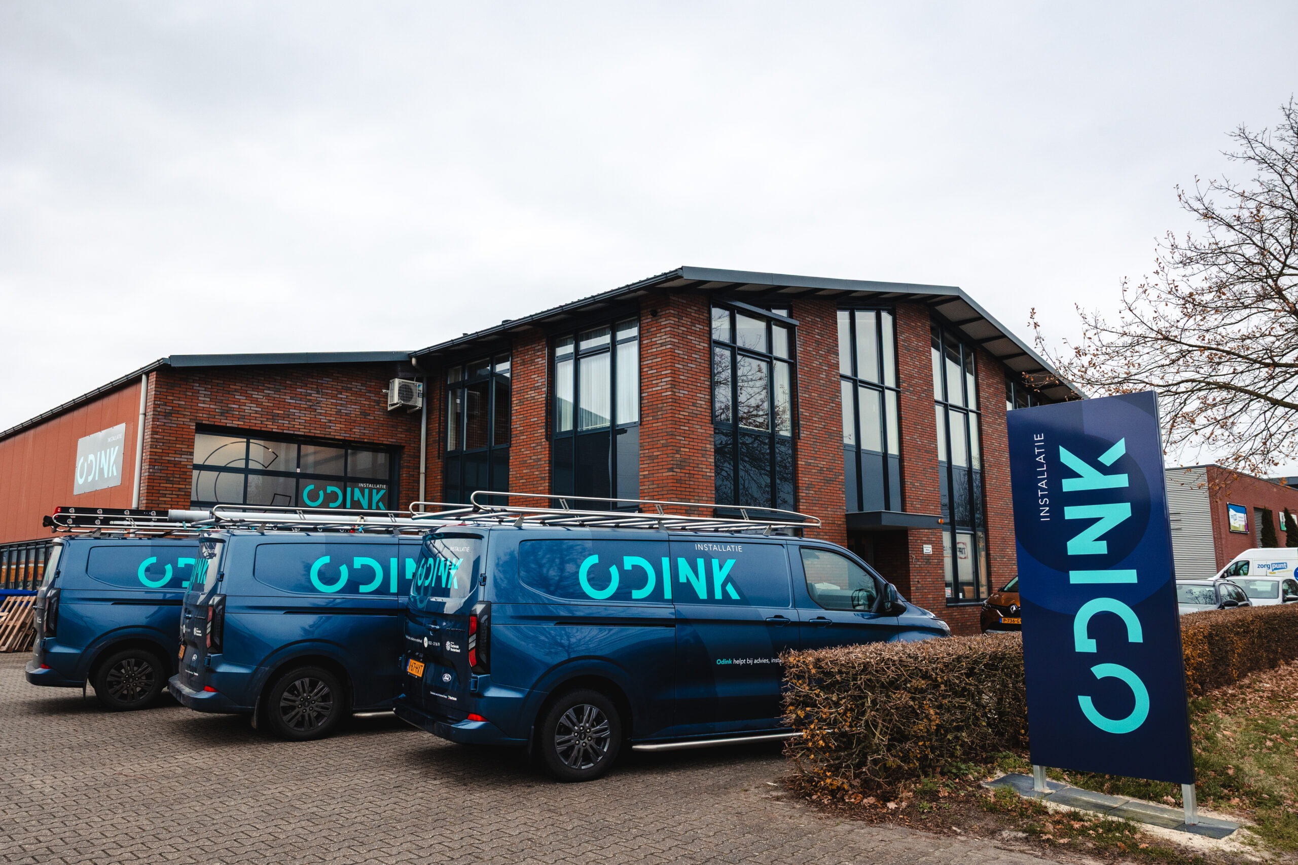 Het pand van Odink Installatie met bedrijfsbussen ervoor